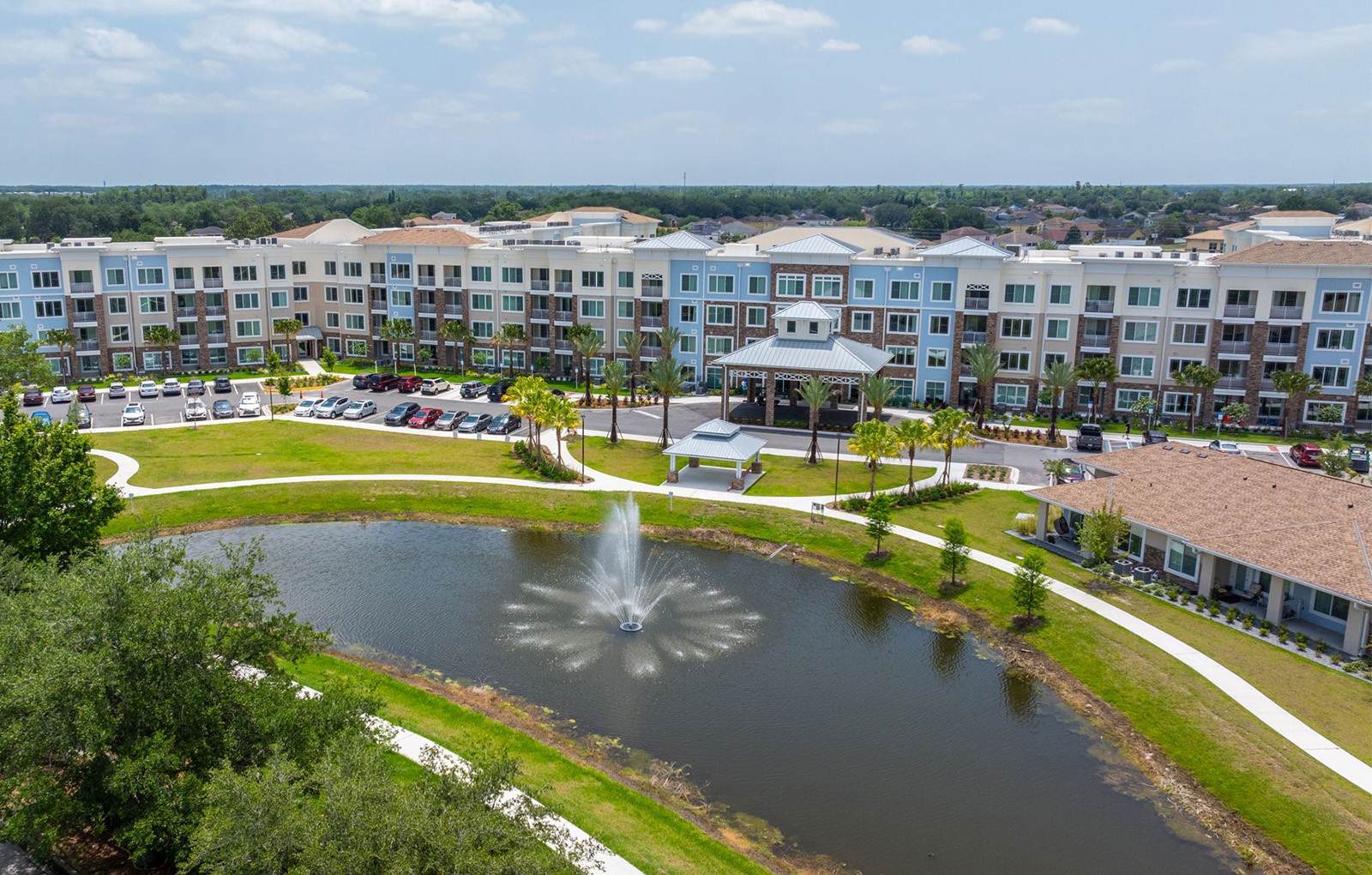 a fountain in the middle of a pond in front of an apartment building